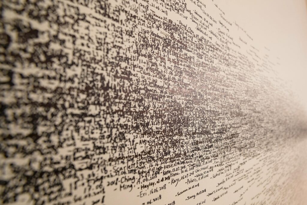 Image of a wall covered with densely packed text creating an abstract pattern.